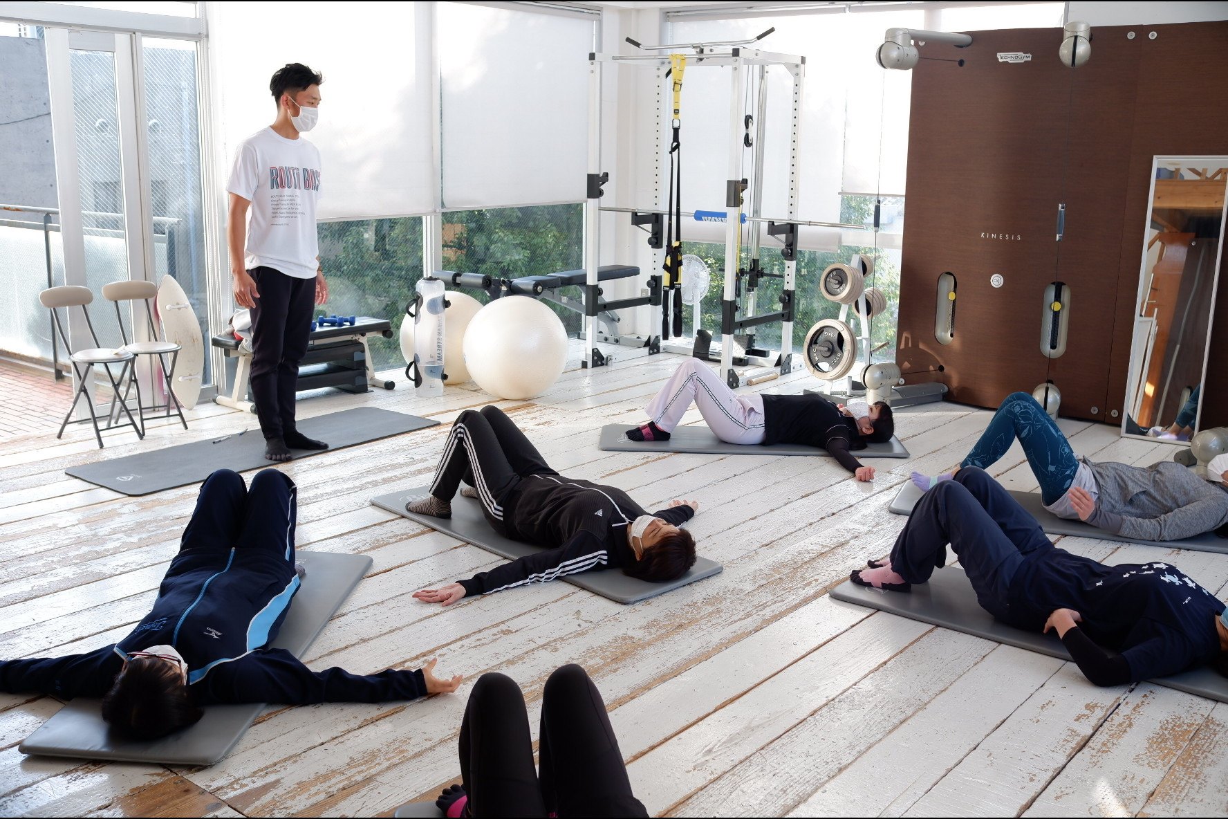 RELI.STYLE FITNESS のスタジオで、会員様がマットの上で体を動かしているグループレッスンの様子